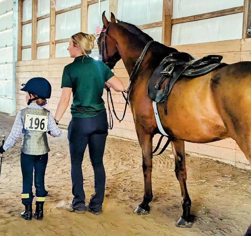 an instructor leading a horse and child